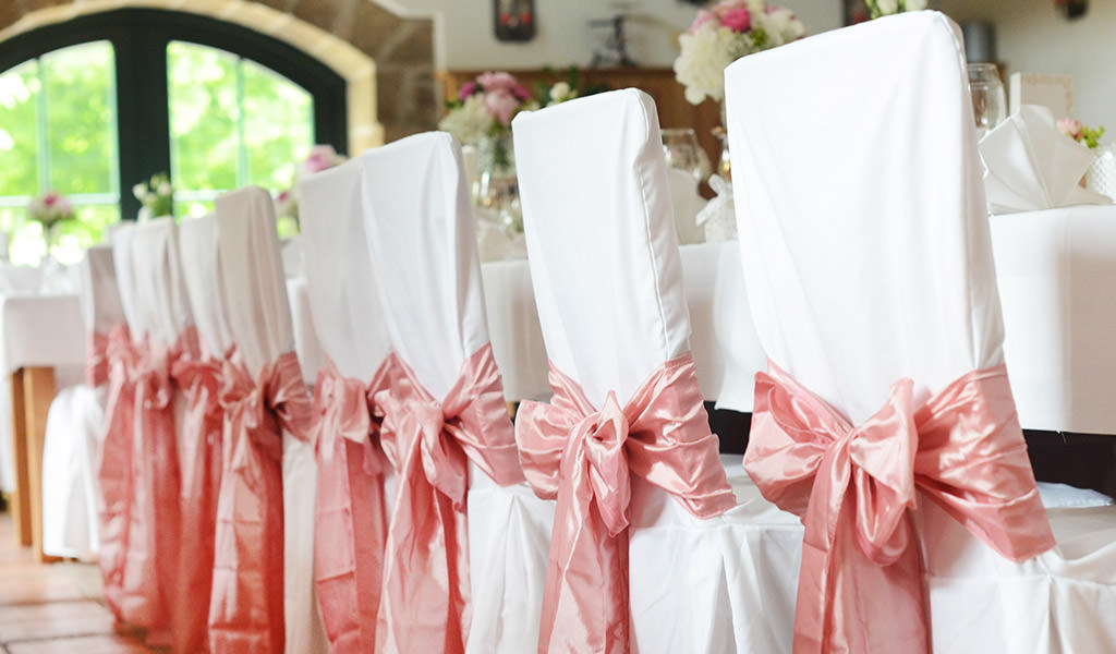 Weiße Stuhlhussen mit rosafarbenen Satinschleifen